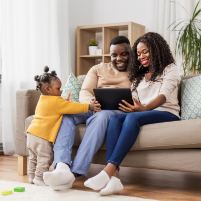 A picture of a mom and dad with their baby on the couch