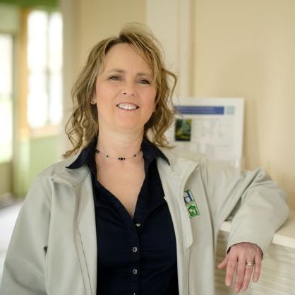 Image of Brook Upton, standing in front of a Neighborhood Housing Services sign smiling into the camera